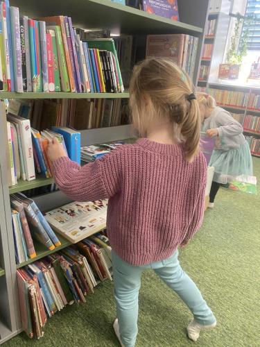 20 dzień postaci z bajek dziewczynka wybiera bajki na bibliotecznej półce
