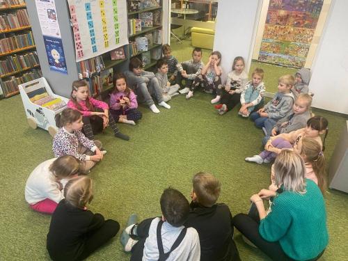 8 dzieci i bibliotekarka Asia podczas lekcji bibliotecznej